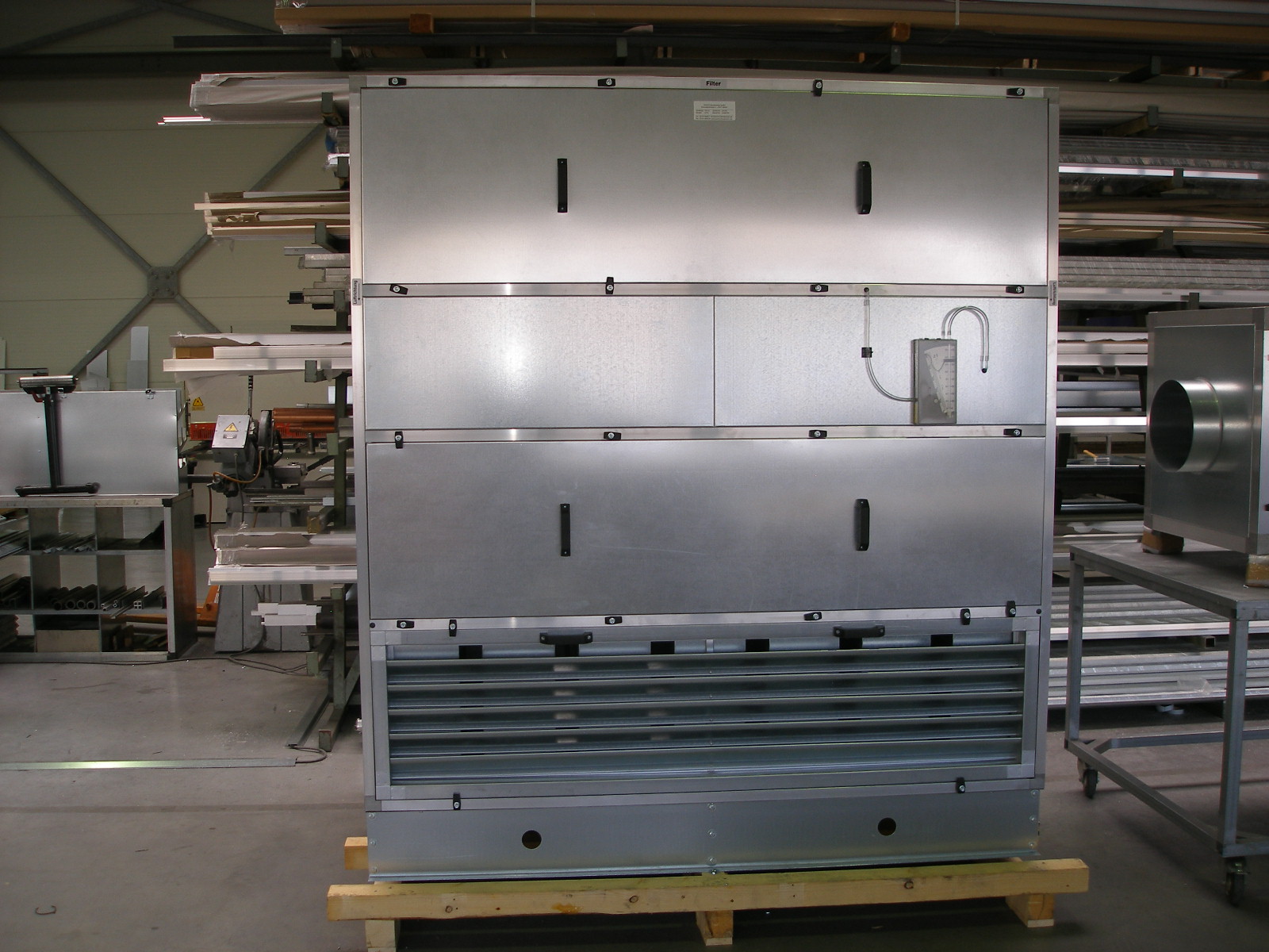 Metall-Lüftungsgerät in Werkstattumgebung, vorbereitet zur Montage oder Wartung.