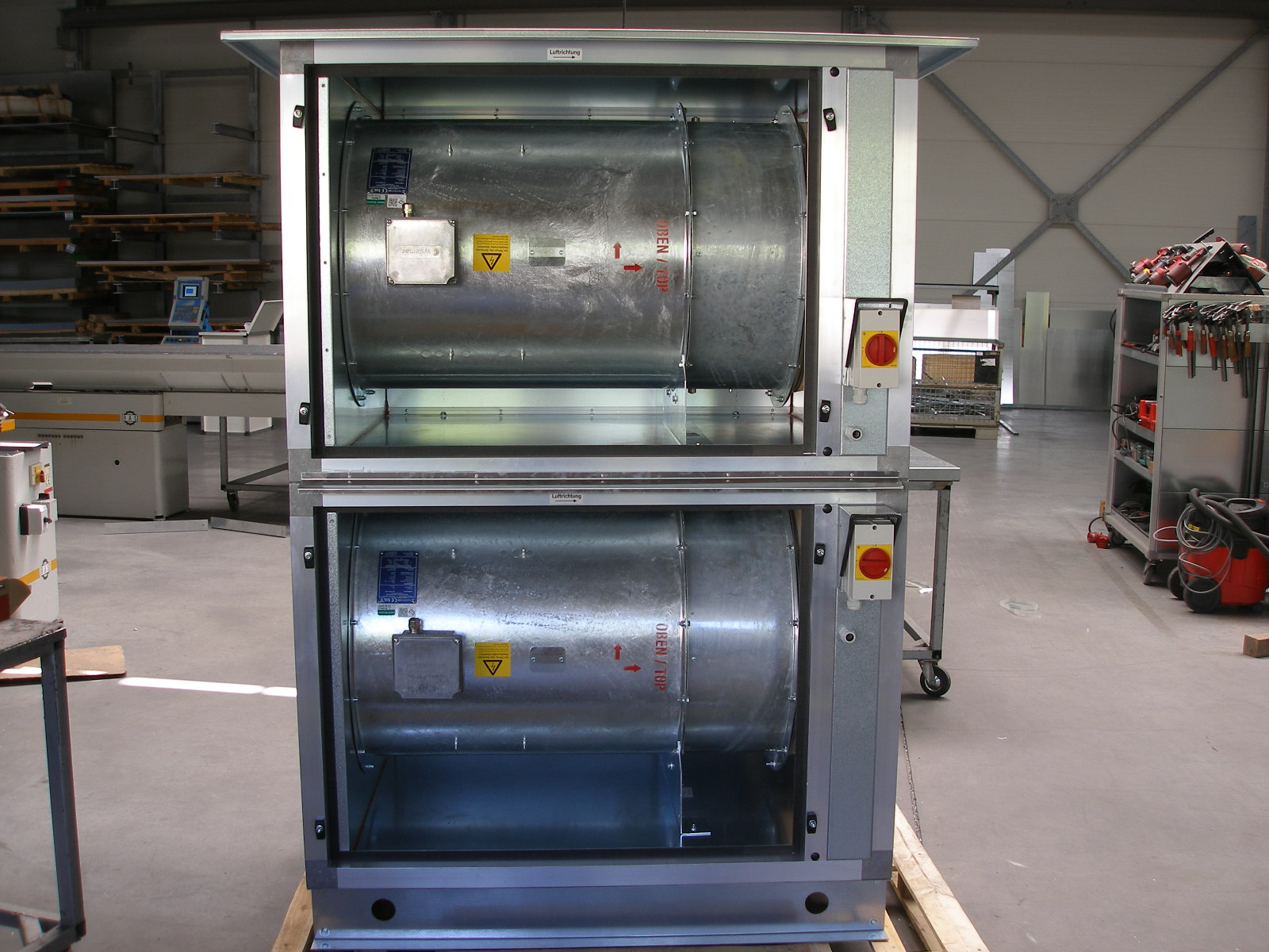 Zweifaches Lüftungsmodul mit sichtbaren Ventilatoren in offener Werkstattumgebung.